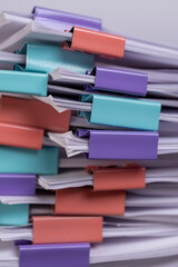 white sheets of paper are connected by multicolored metal clips, stacked sheets of paper for...