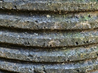 Close-up of weathered corrugated surface with moss, dirt, and erosion texture details