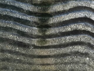 Close-up of weathered corrugated surface with moss, dirt, and erosion texture details