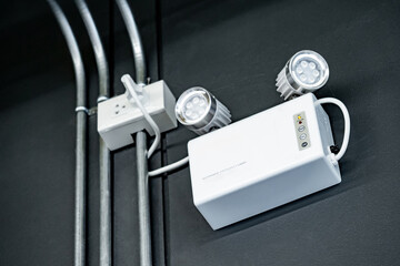 LED Automatic emergency light mounted on black wall in industrial warehouse or factory building. Backup on battery when power outage
