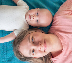 Mother and baby share a joyful moment lying on a blue blanket in a cozy indoor setting