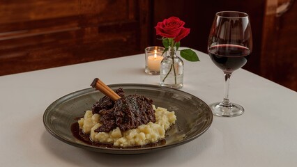 A meal featuring meat and smooth mashed potatoes alongside a glass of red wine on a table.