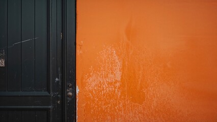 A jet-black door on a vivid orange wall
