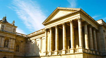 Obraz premium Majestic neoclassical architecture with grand columns and ornate details bathed in bright sunlight against a clear blue sky