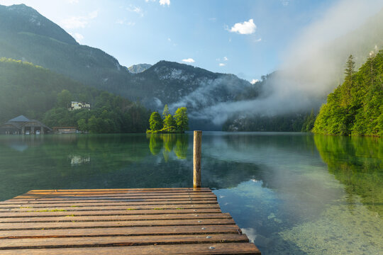 Mystischer Morgen am K&ouml;nigssee in Sch&ouml;nau mit Bootsh&auml;usern und Christlieger. Sonnenaufgang und sch&ouml;ne Nebelschwaden &uuml;ber dem K&ouml;nigssee im Kessel.