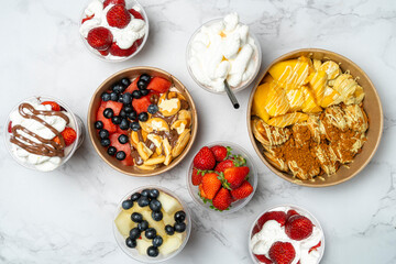 Colorful dessert bowls with mini pancakes, fresh fruit like mango, strawberries, blueberries,...
