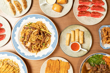 Overhead shot of various asian dishes arranged on a wooden table, representing diverse culinary traditions