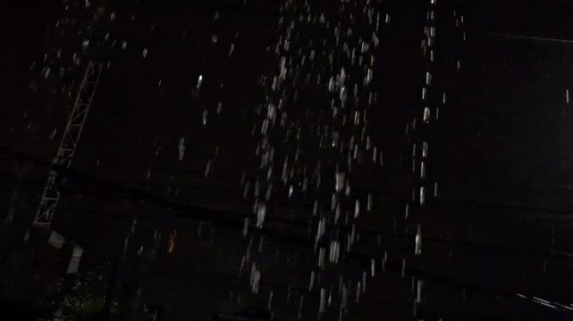 Heavy rain falling at night, creating a soothing, atmospheric scene with water droplets glistening in the dark. Ideal for weather-related content, rainstorms, and rainy night footage on Adobe Stock