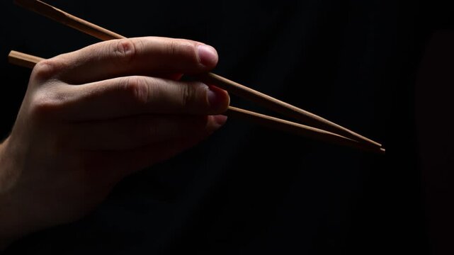 Japanese chopsticks for sushi and traditional Asian food.
Technique of using Chinese chopsticks in restaurants.
Asian man's hand holding bamboo chopsticks