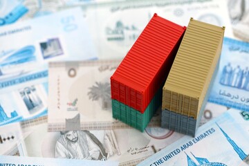 United Arab Emirates dirham currency money bills and toy cargo containers. The concept of shipping...