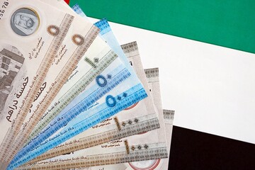 United Arab Emirates dirham currency money bills lies on flag. The concept of business and...