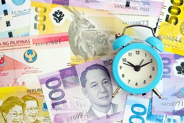 Philippines peso currency money bills and alarm clock. The concept of time management and income