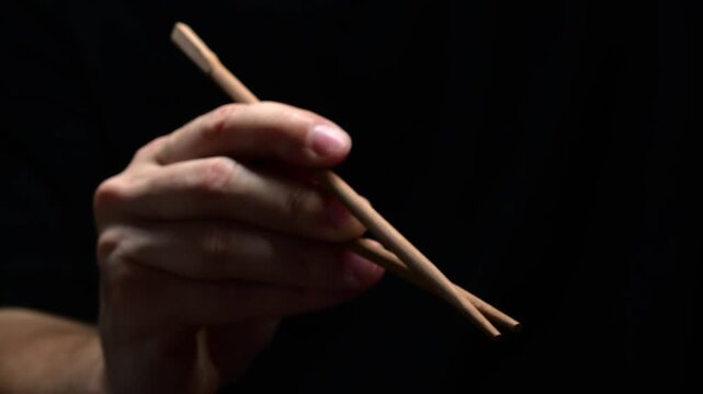 Japanese chopsticks for sushi and traditional Asian food.
Technique of using Chinese chopsticks in restaurants.
Asian man's hand holding bamboo chopsticks