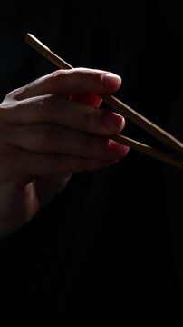 Using Japanese or Chinese chopsticks in a restaurant on a black background.
Bamboo chopsticks in Asian culture.
Ancient Asian food traditions and eating culture