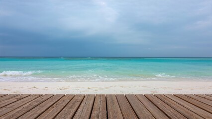 Fototapeta premium In warm weather, an attractive shoreline with white sand stretches out. The sky shows an overcast blue tone, and the water gleams turquoise. Holiday backdrop with natural scenery, blurred effect, and