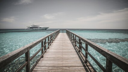 Artistic black and white photograph showing a wooden pier, yacht, and ocean scene