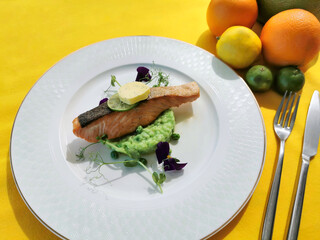 Sous Vide Salmon with Pea Mint Risotto served in plate with orange and lemon closeup side view of a gourmet meal