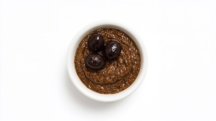 A ramekin filled with black olive paste displayed on a white surface