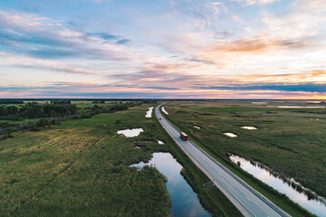 Vehicles travel along a highway through the green countryside at sunset