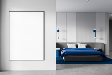 Minimalist bedroom interior with blank framed poster on wall and modern decor elements in white and...