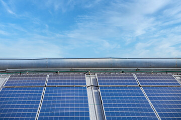 Solar Panel Photovoltaic installation on a Roof of factory, sunny blue sky background, alternative...