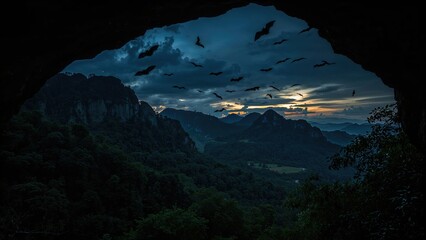 Black bats taking flight from mountain caves at dusk, set against a natural forest and blue sky