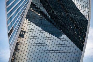 mirrored windows of the facade of an office building with blue panels