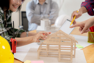 Group of architects examining a building model, discussing modern design and construction technology in a collaborative workspace.