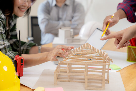 Group of architects examining a building model, discussing modern design and construction technology in a collaborative workspace.
