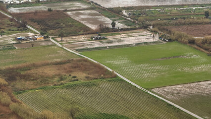 Aerial view of rain-swept patchwork fields captures serene agricultural symphony, connected to...