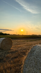 Golden hay bales bask in twilight's embrace, echoing harvest solstice's quiet splendor and ancient Lammas celebrations © fotoworld