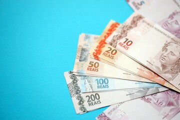 Close up brazilian reais money bills in big amount on blue. Pile of Brazil real currency banknotes