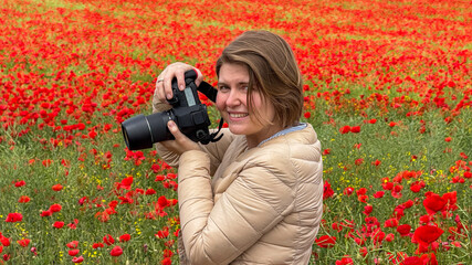 A smiling Caucasian woman photographer amidst blazing poppy fields, celebrating World Photography Day and the vibrant Floralia festival