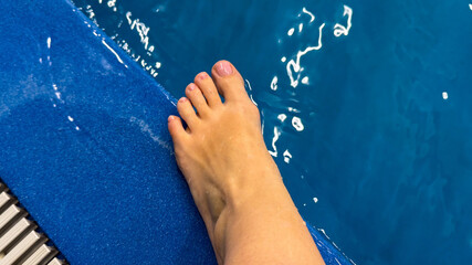 A Caucasian female's foot playfully skims a crystalline pool edge, evoking Midsummer rituals and...