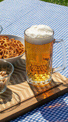 A frothy beer mug glows in Oktoberfest sunlight beside twisted pretzels, evoking Bavarian traditions and lively biergarten festivity