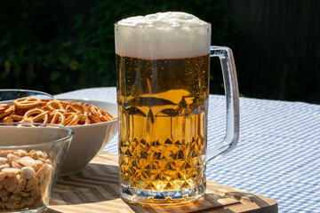 Glimmering frothy stein of golden lager beside crunchy pretzels, evoking Oktoberfest jubilation and International Beer Day merriment