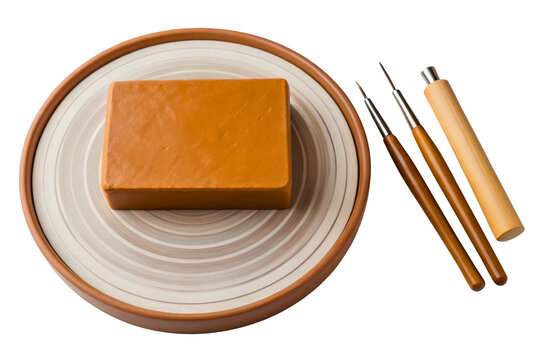 Pottery sculpting wheel with orange clay block and carving tools isolated with transparent background - Powered by Adobe