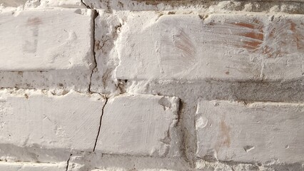 old white brick wall with cracks between the bricks