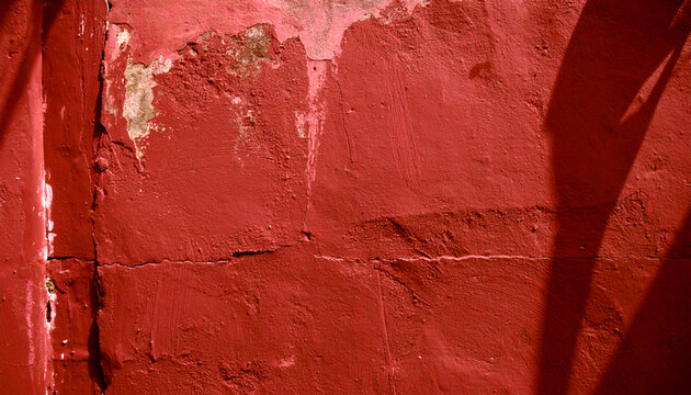 Aged Crimson Plaster Wall: A Textured Study of Decay and Shadow
