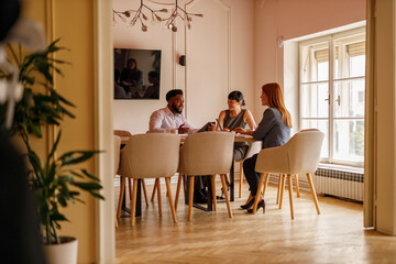 Businessman discussing and brainstorming strategies to female coworkers while collaborating in...
