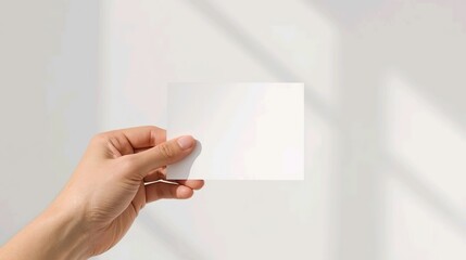 Obraz premium Hand Holding a Blank Postcard with Natural Light Shadows