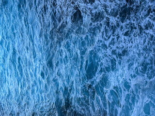 Blue sea water texture with frothy waves. White foam texture background with turquoise and blue...