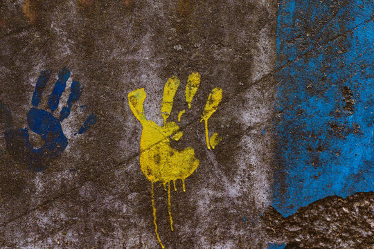 Colorful handprints in yellow and blue on a weathered textured concrete surface, creating a vibrant and artistic expression. Love and support Ukraine in war. Ukraine loves. Ukrainian kids childhood. - Powered by Adobe