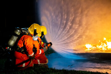 Firefighter training, fireman using water and extinguisher to fighting with fire flame in an...