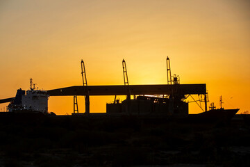 Amanecer en un puerto con buque a contraluz