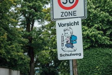 Tempo-30-Zone mit Achtung-Schulweg-Schild im Wohngebiet als Sicherheitsma&szlig;nahme f&uuml;r Kinder Fu&szlig;g&auml;nger und Sch&uuml;ler im Stra&szlig;enverkehr in einer ruhigen Nachbarschaft