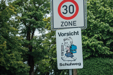 Verkehrsschild im Wohngebiet mit Tempo-30-Zone und Schulweg-Warnung sorgt f&uuml;r mehr Sicherheit von Kindern und Fu&szlig;g&auml;ngern im st&auml;dtischen Stra&szlig;enverkehr