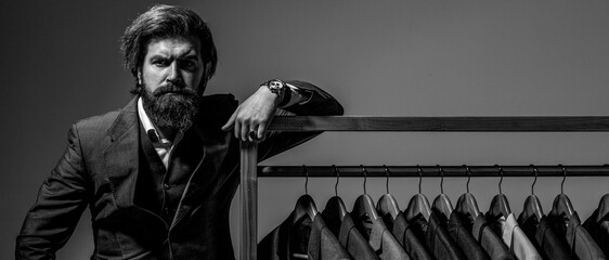 Man with suit. Man clothing in boutique. Male suits hanging in a row. Man with suit. Tailor in his...