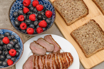 A healthy and varied breakfast, dark rye bread, fruit and homemade baked meats