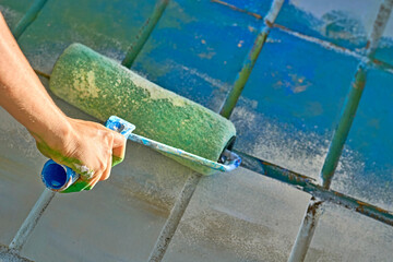 Repairing.Roller painting wall surface with blue paint